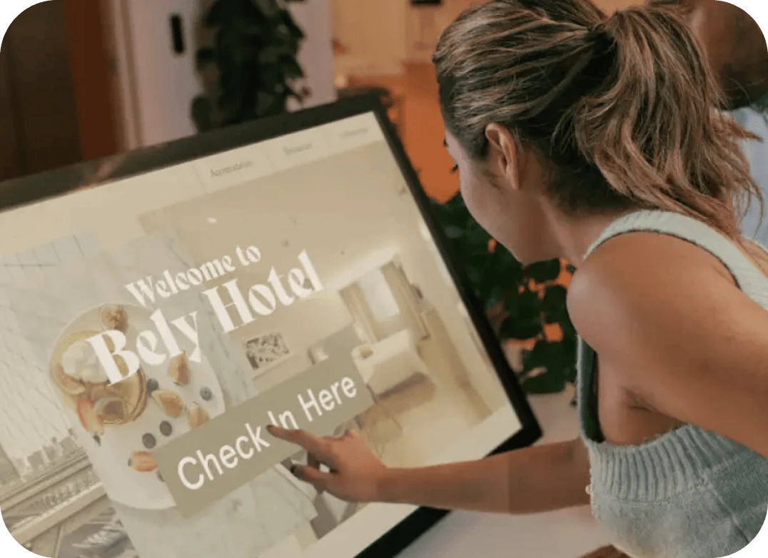 A woman touches the check in button on an interactive digital signage kiosk to check into a hotel