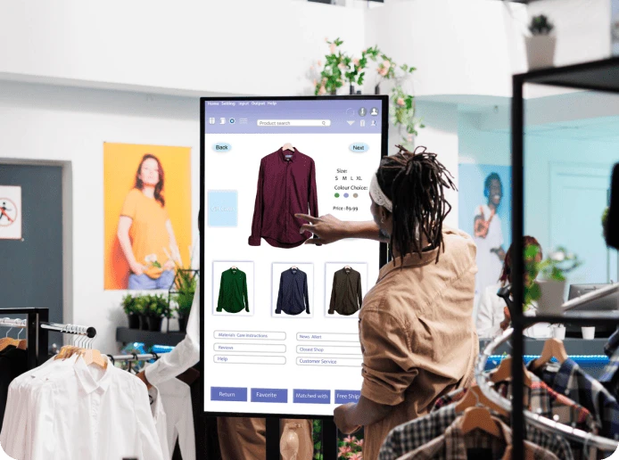 A woman stands at an interactive retail kiosk in a store and selects an item of clothing from the app