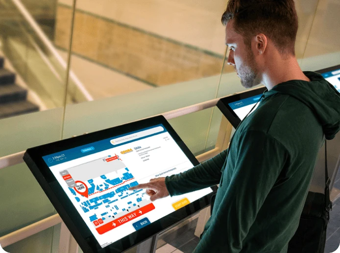 A student uses an interactive touch screen kiosk to navigate around the university's floor plan map