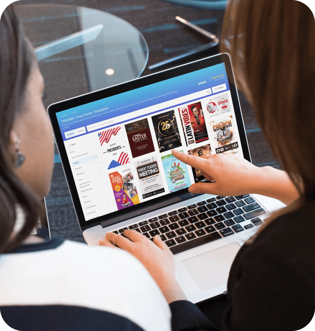 Two women look at a laptop with PosterMyWall open in the browser.